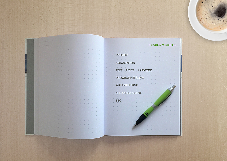 Aufgeschlagenes Notizbuch auf einem Tisch mit Werbekeywords wie Projekt, Konzeption oder Programmierung